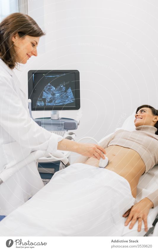 Female doctor making ultrasound scan to woman patient sonogram clinic fertile pregnancy women smile medicine belly practitioner happy pregnant work contemporary