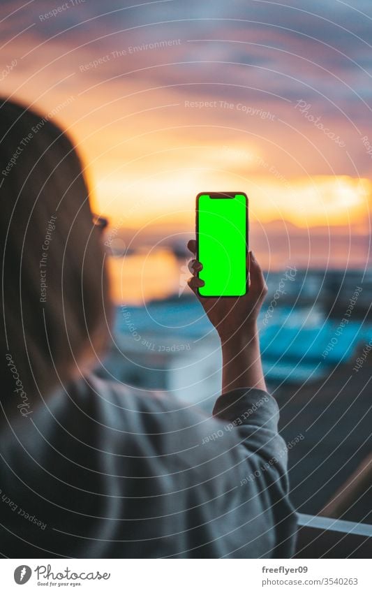 Woman holding a smartphone on a green screen photo photography photographing taking photographs picture hand technology shot using mobile mobile phone device