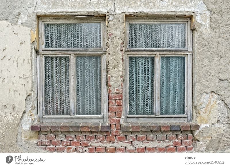 two old, whole wooden windows with curtains in a dilapidated wall Window Curtain Poverty Decline object of speculation Wooden window outlook Wall (building)