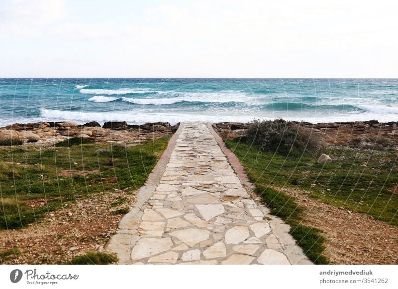 In the foreground a concrete walkway that crosses a pebbles and stone beach. selective focus. ocean sea sky beautiful tourism travel blue landscape water summer