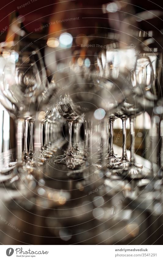 empty wine glasses. Beautiful new glasses for wine from glass stand in even rows on a wooden table in a restaurant. selective focus alcohol bar celebration