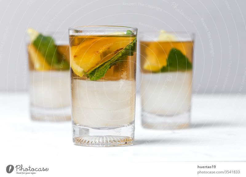 tea with ice, mint and lemon wedges on white table cold drink iced glass refreshment sweet cube cool liquid background beverage summer food healthy green