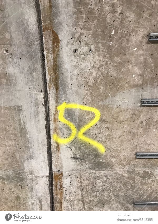 Yellow number 52 sprayed on concrete wall. Marker. Numbers. figures Spray Graffiti mark Wall (building) Colour photo Wall (barrier) Digits and numbers Sign