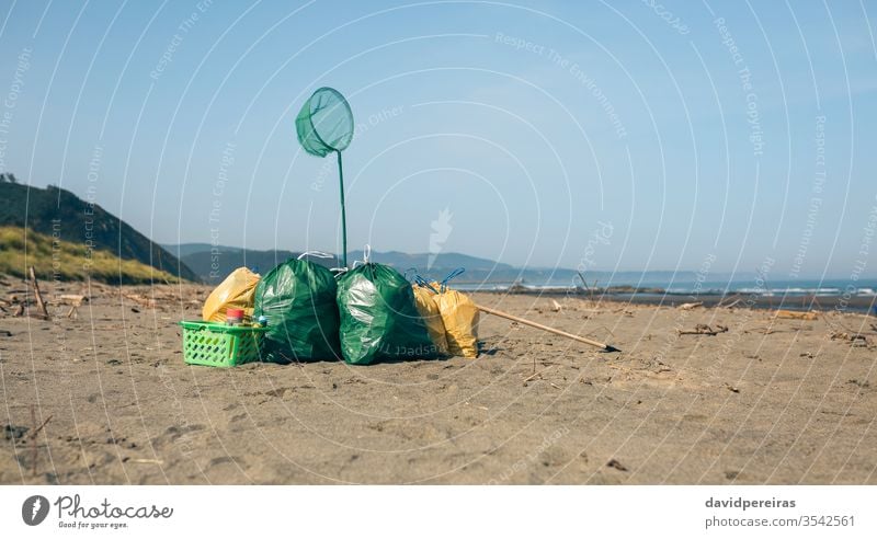 Garbage bags and utensils on the beach garbage bags after clean trash collected environmental awareness sand nature waste coast problem litter shore polluted