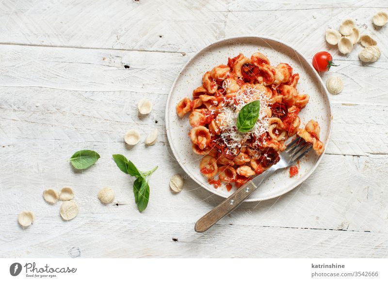 South italian  pasta orecchiette with tomato sauce and cacioricotta cheese apulia tomatoes sugo top view white basil green herbs leaves copy space wooden cooked