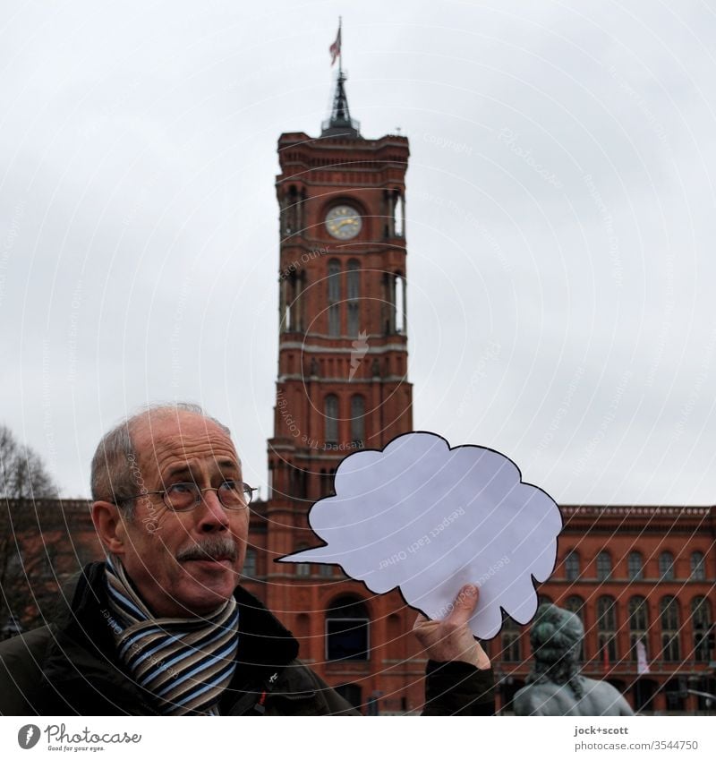 Smiling with an empty speech bubble in the middle of the capital Man without words portrait Front view Rotes Rathaus Capital city Downtown Tourist Attraction