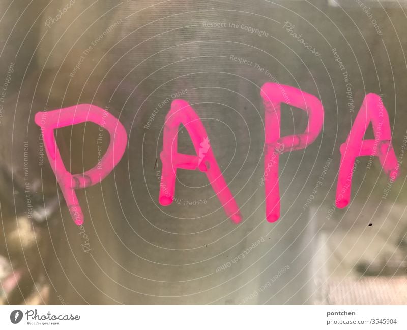 The word papa is written in children's letters in pink on a window. Father's Day dad Word children's handwriting window painting Child Family & Relations