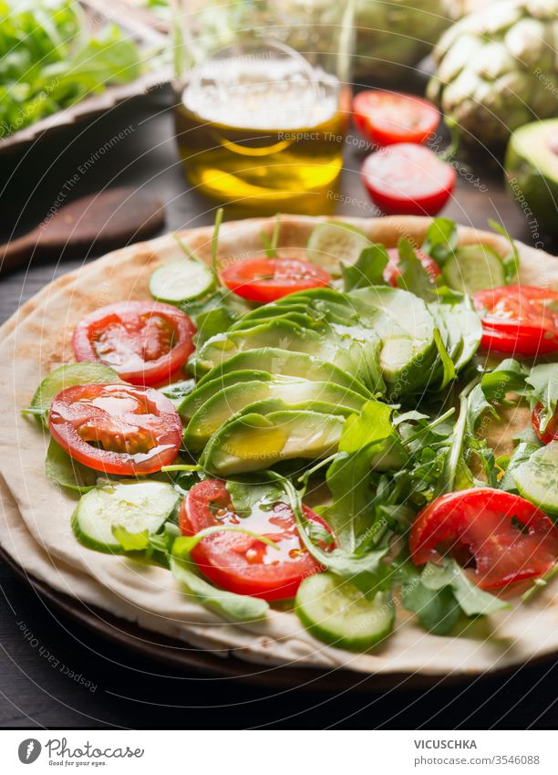 Cooking delicious tortilla with cherry tomatoes, avocado, cucumber, arugula and olive oil. Healthy food. Close up. wrap vegan flat-bread ingredient taco