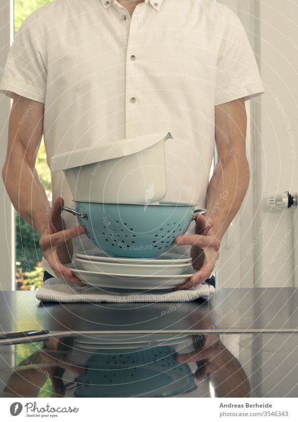 A middle-aged man in a kitchen holding washing dishes equipment service carrying husband smile sink european male activity house clean chores plate person