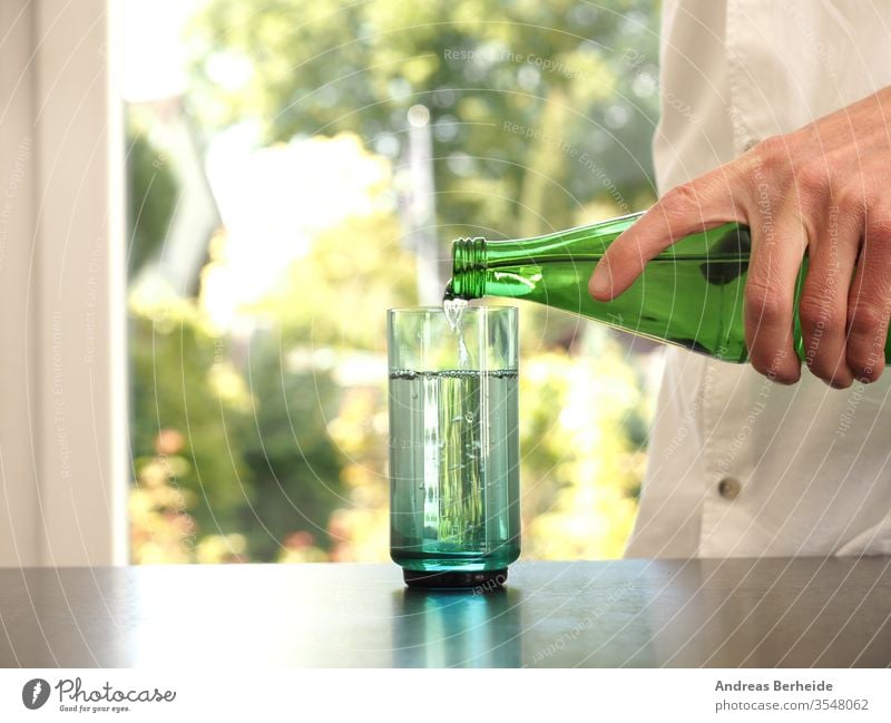 Mid aged man pouring water into a glass purity healthcare aqua fitness wellbeing mineral human blurred table person thirsty clear hold full garden bokeh wooden