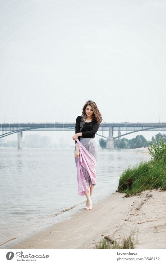 Young female walking on a beach with a pink scarf in her hands, selective focus adult back beauty bride caucasian dress faceless girl lifestyle model moving