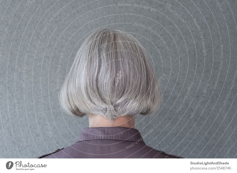 Silver-haired lady on gray background head grey purple silver haircut hairdo hairstyle person woman female 50s 60s feminine fashion fashionable casual shirt