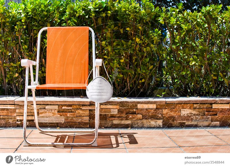 Orange chair with protective face mask and trees landscape covid-19 virus pandemic concept health illness protection during wear water hotel resort holidays