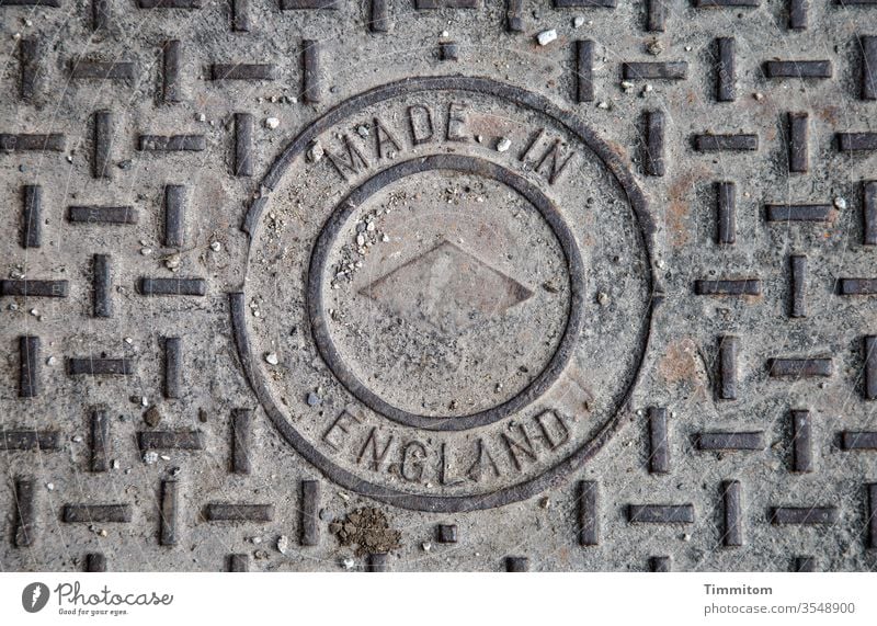Manhole cover - Made in England Metal Pattern Great Britain country of origin Industry Old Exterior shot stones Sand