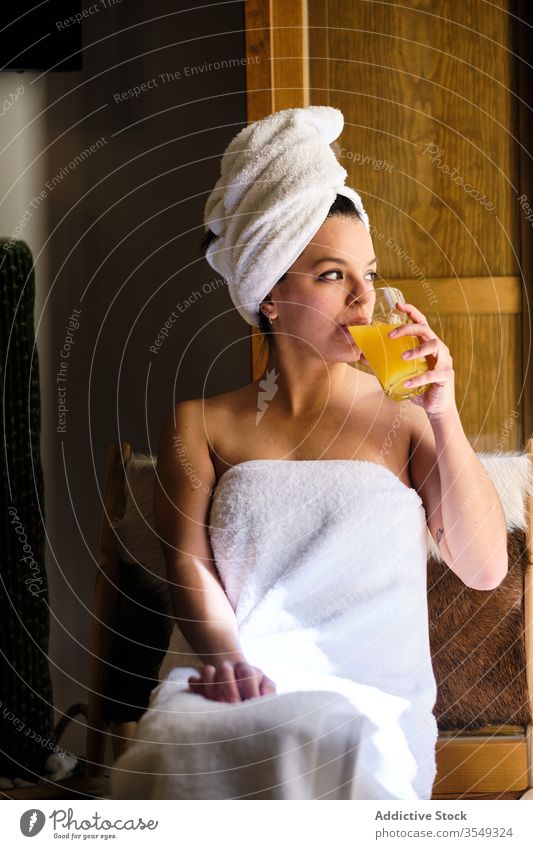 Dreamy young woman sitting in towel and drinking fruit juice morning wet shower chill harmony contemplate dreamy relax rest daytime meditative wellness orange
