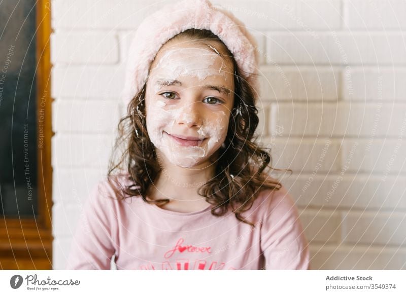 Cute girl with white face mask child pajama skin care smile headband portrait glad little pink kid natural home cosmetic healthy cute wellness wall brown eyes