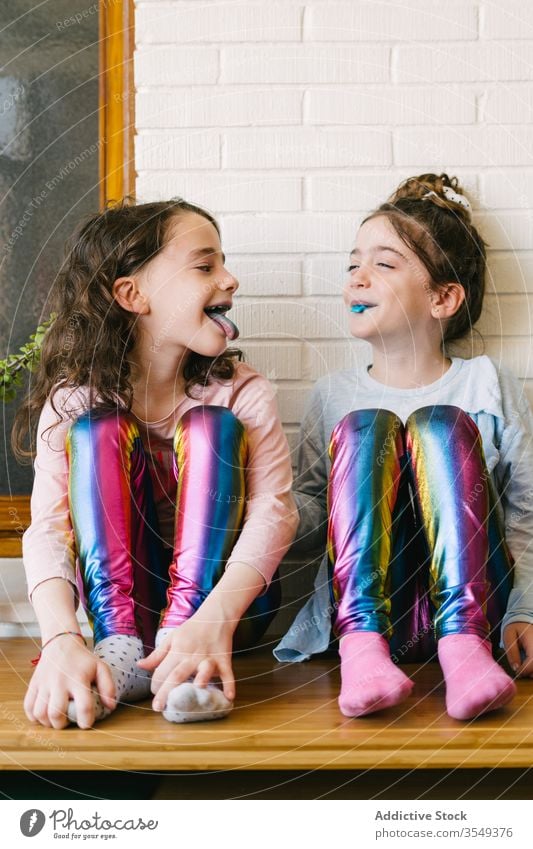 Cheerful little girls eating blue chewing candy treat sweet share home fun happy children tasty laugh yummy sister pajama cozy relax childhood playful enjoy