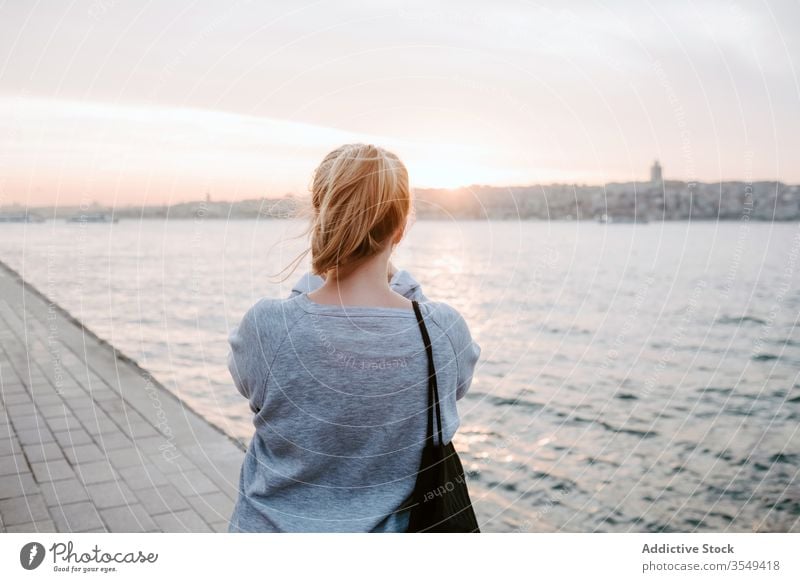 Young woman admiring view of sunset platform observe reflection sea promenade pink light calm horizontal traveler shore nature scenic harmony tourism vacation