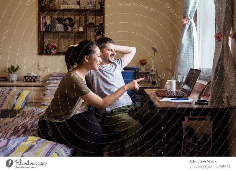 Multiethnic couple in love watching movie on laptop bedroom together discuss video using multiracial multiethnic diverse asian young casual outfit apparel wear