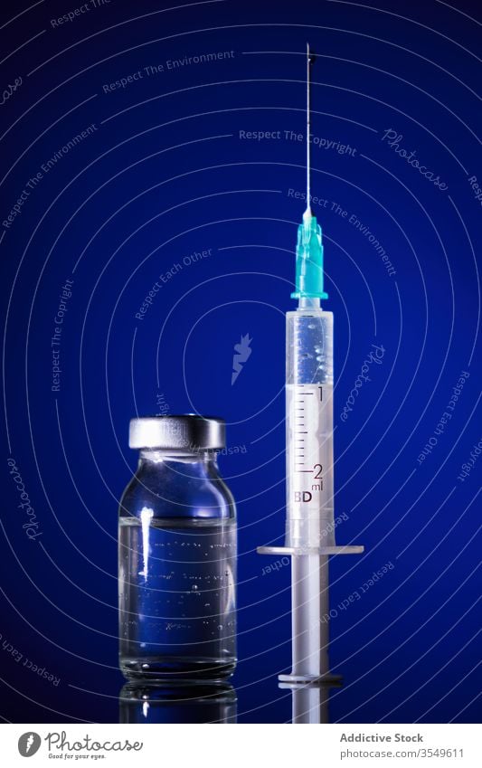 Small bottle of medicine and syringe on blue background vaccine remedy virus infection cure heal covid 19 coronavirus treat medication antibiotic painkiller aid