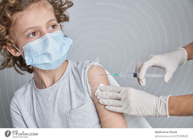 Anonymous doctor holding boy shoulder during injection in clinic vaccine treat syringe medicine glove patient health care procedure work healthy cure kid tool