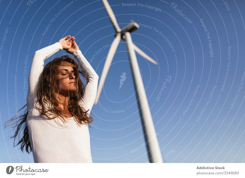 Tender female dancing alone near wind farm on sunny field woman dance countryside sensual nature ecology slim style hand up alternative windmill energy move