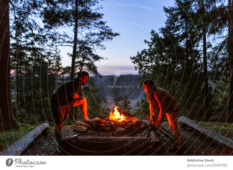 Couple with firewood making campfire in forest couple camper bonfire night log warm up friends traveler woods enjoy evening woman together relax nature love