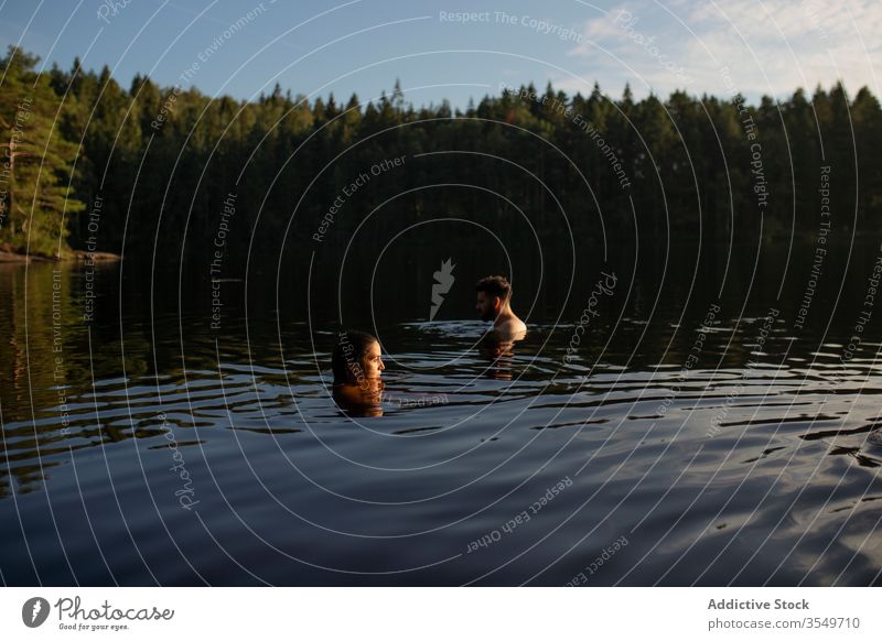 Man and woman swimming in forest lake in summer couple travel nature together trip relax sun harmony daytime weekend calm clean sunny vacation leisure water