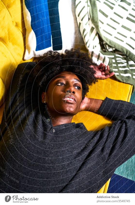 Young black woman resting on colorful sofa home lying bored pensive design thoughtful dream young african american female casual couch ethnic isolation relax