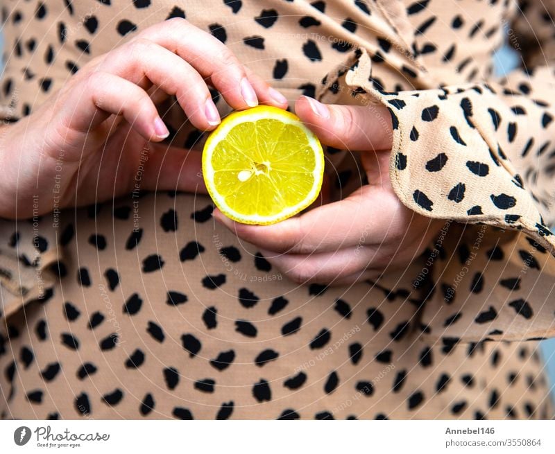 Young beautiful woman holding a fresh yellow lemon in her hands, close-up summer fruit concept background fashion water food person girl dress wine texture