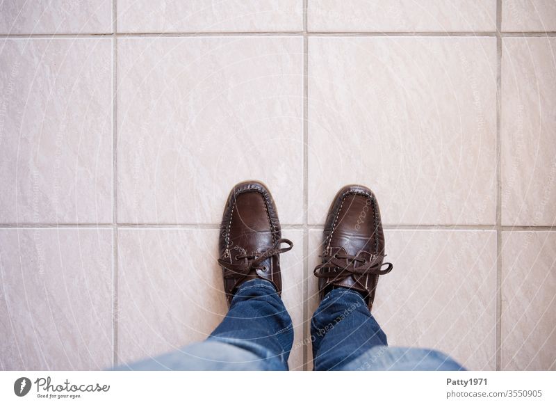 Person stands on tiled floor. View from above on the shoes/legs and the floor Copy Space top Footwear floor" feet Stand Tile conceptually person Ground
