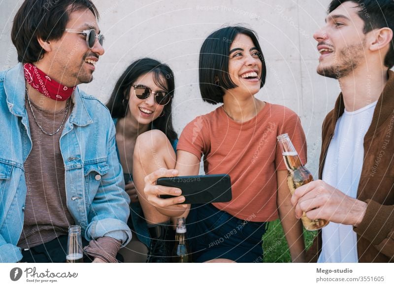 Group of friends watching something in smartphone. mobile friendship lifestyle portrait holding smart phone urban modern meeting joy enjoyment enjoying