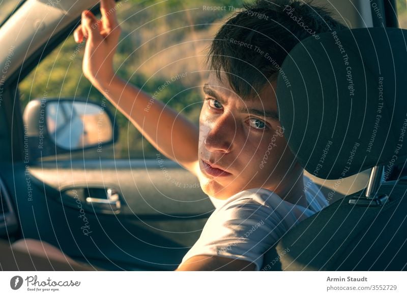 portrait of a young man sitting in a car back beautiful boy casual caucasian co-driver confident cool eyes headrest indoor inside journey lifestyle looking male