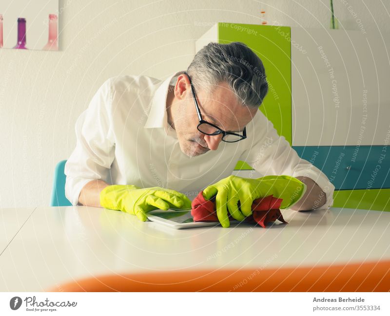 Middle-aged man thoroughly cleans a tablet computer adult attractive bearded caucasian chores cleaner cleaning cleansing clear concentrated domestic focused