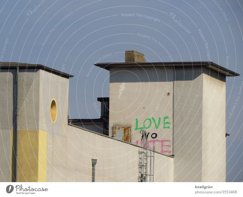 Building with two towers, on one of them a graffiti LOVE NO HATE Graffiti built Love Wall (building) Wall (barrier) Fire ladder Tall Flat roof Blue sky