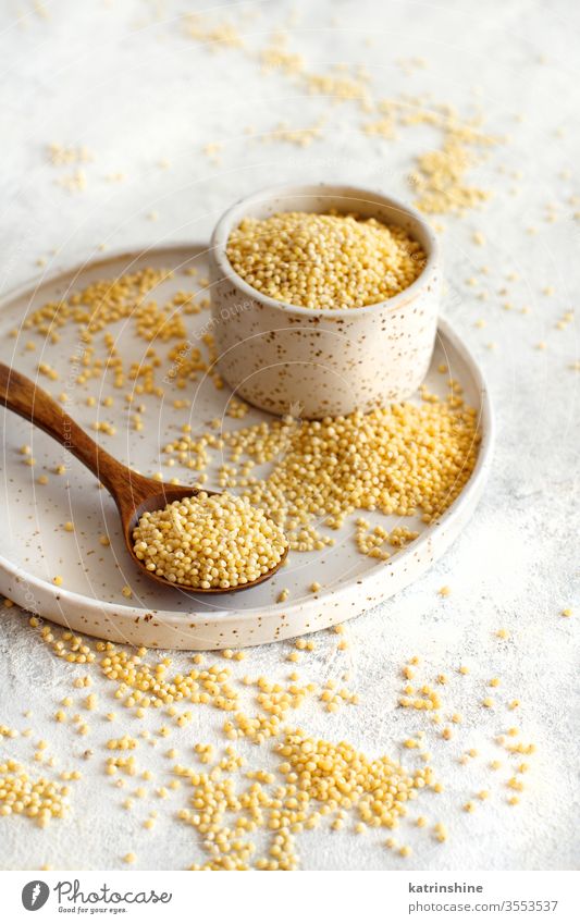 Raw dry hulled millet in a ceramic bowl raw spoon close up diet dried fiber food healthy ingredient grey copy space negative space natural nobody nutritious