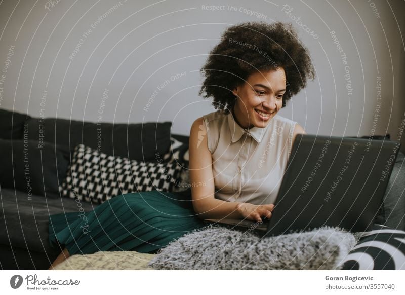 Attractive young woman working on laptop at home female computer people professional person business one technology african using internet curly black sitting