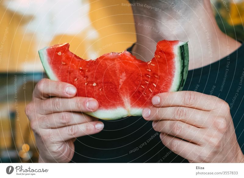 A man is holding a bite of watermelon in his hand Water melon Eating bitten into Bite Delicious Summer Red Fresh Mature Fruity Man Nutrition Juicy