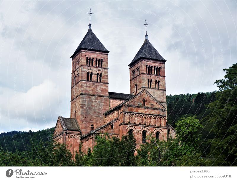 Steeples of Murbach Abbey looming out of the forest in the Vosges church religion architecture old historic medieval building ancient tower monastery