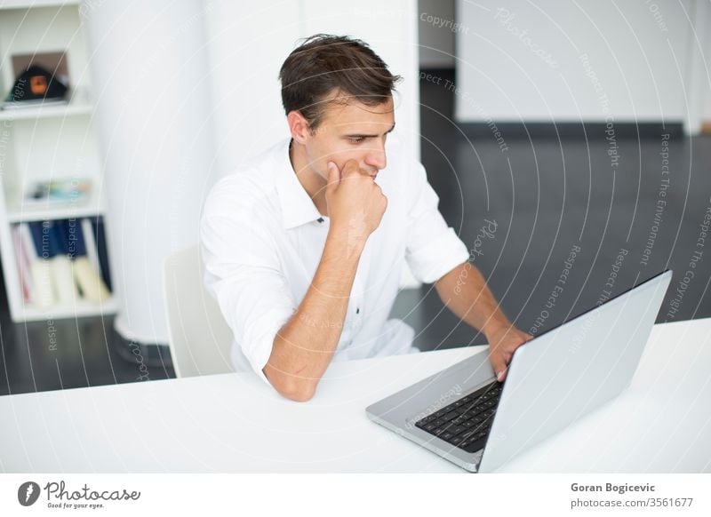 Young man in the office business desk laptop looking handsome corporation issue white sitting adult copyspace determined occupation light involved one caucasian