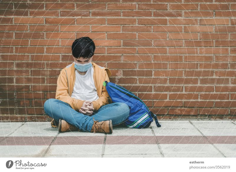 sad kid with medical mask and backpack coronavirus child epidemic covid-19 school student pandemic quarantine city schoolboy sadness preoccupation dejected
