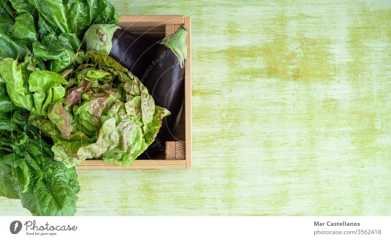 Wooden box with vegetables on a green wooden base. Copy space. Concept Vegetables. vegan wooden box green background vegetable box eggplant lettuce chard