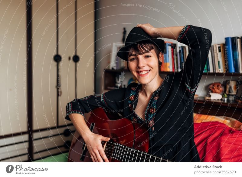 Smiling woman playing guitar in bedroom music acoustic instrument calm smiling tranquil trendy female melody sound sit hobby musician song relax style tune lady