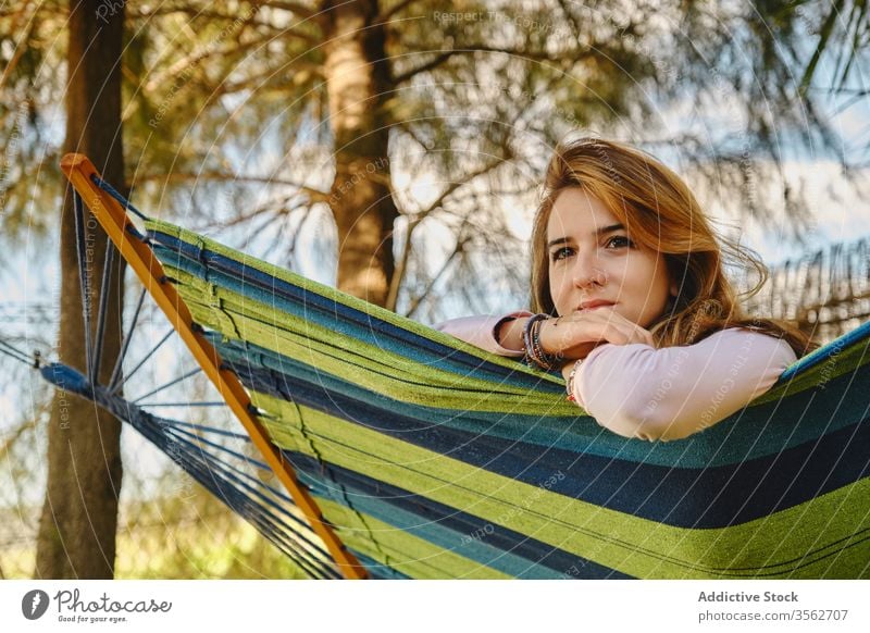 Relaxed woman in hammock in the sunset relax calm lying courtyard enjoy female summer holiday vacation weekend casual outfit lady rest peaceful tranquil young