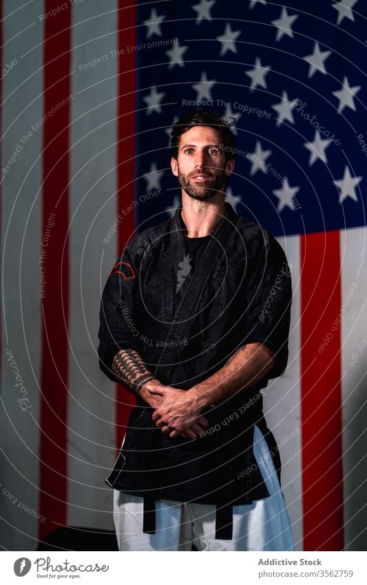 Confident man in black kimono looking at camera martial strong bearded confident serious fighter portrait adult american flag practice male training kajukenbo