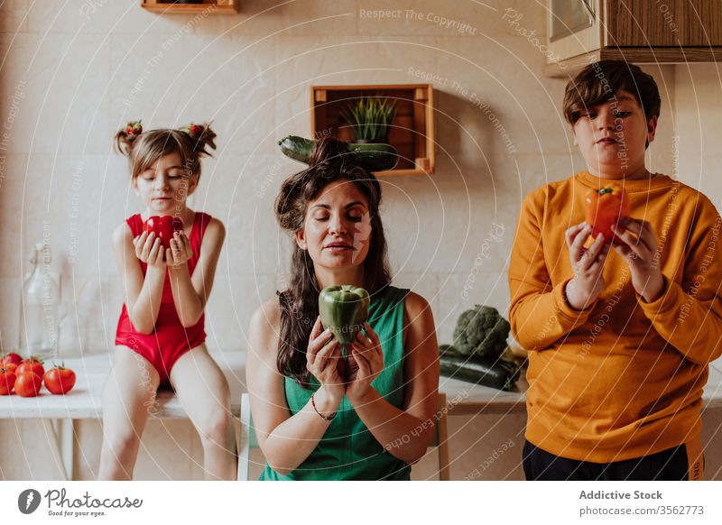 Mother and children obsessed with vegetables mother pepper pray concept kitchen diet healthy colorful home cozy teen kid girl boy sibling woman daughter son