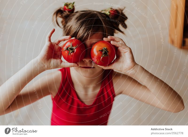 Little girl having fun with tomatoes kitchen home eye concept red bright color fresh cute kid child play cozy vegetable joy food vitamin healthy diet vegan