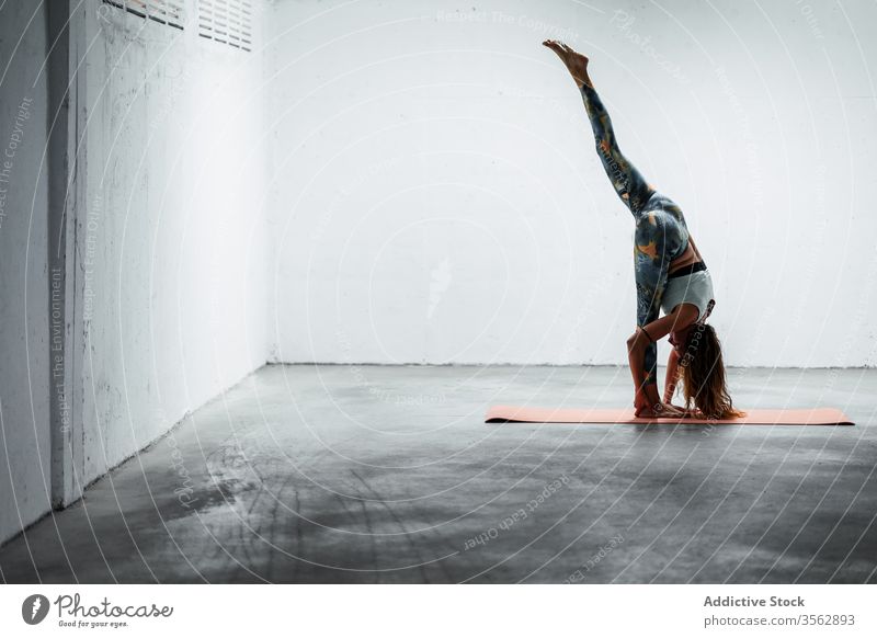 Tranquil woman doing standing split on mat yoga practice flexible balance tranquil harmony female calm pose slender asana slim floor sportswear active wear lady