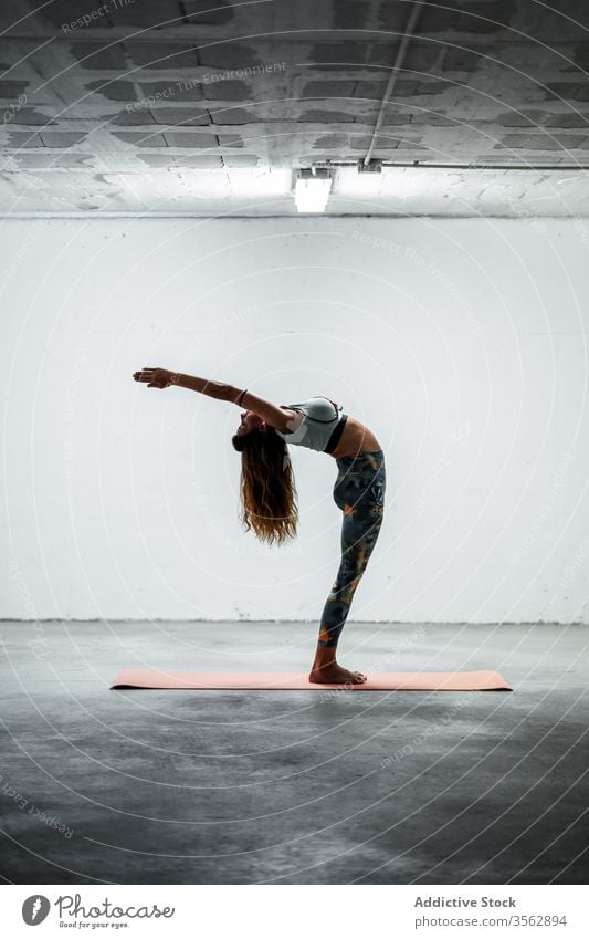 Slender woman doing yoga in Mountain pose with raised arm balance practice calm standing backbend slender asana female slim mat flexible floor sportswear