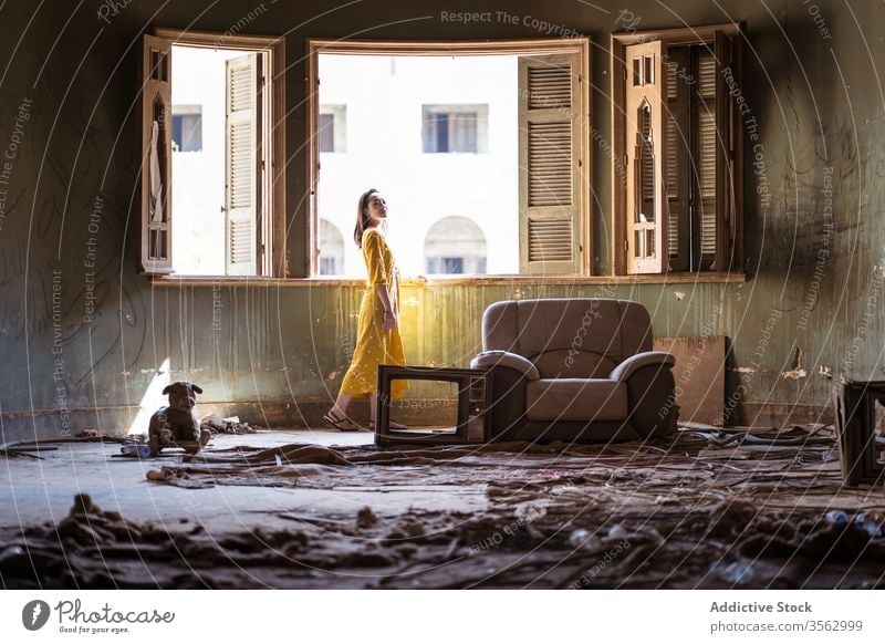Woman standing in living room of abandoned house woman window uninhabited old shabby messy apartment residential young ethnic female saudi arabia jeddah asian